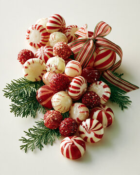 beautiful Christmas candy arrangement with red, white and cream sweets, peppermint inspired shapes without branding, festive ribbons and evergreen branches, clean premium studio background,