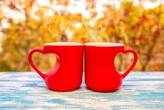 two heart shaped mugs with tea on natural autumn  background
