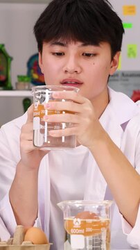 Teenage Student in Lab Coat Examining Science Experiment with Beaker