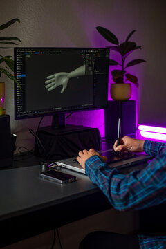Digital artist at desk using graphics tablet and 3D software