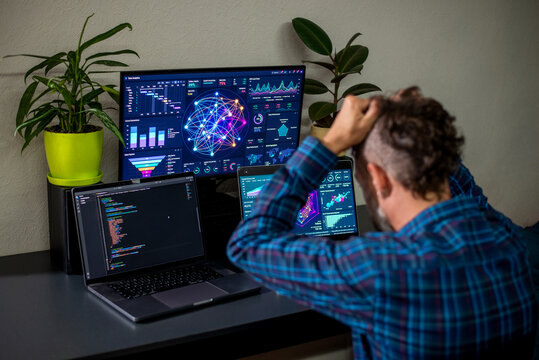 Data analyst frustrated in home office with multiple monitors