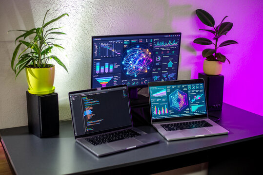 Modern workspace with multiple laptops and analytics monitor