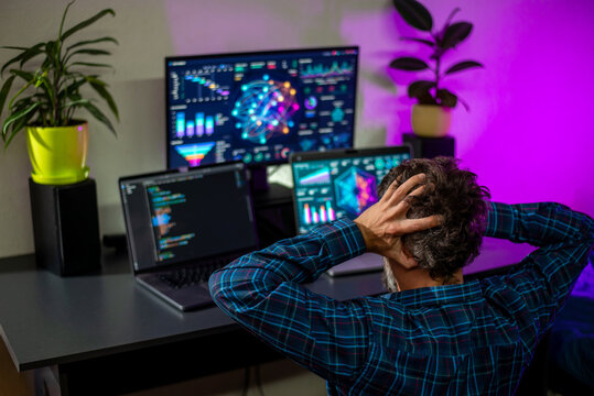 Frustrated programmer at multi-monitor data visualization workspace