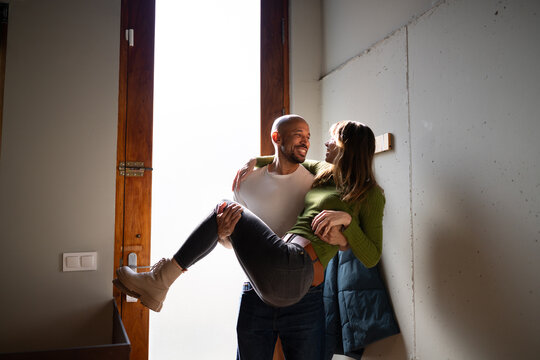 Man carrying woman over doorstep at home