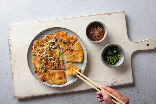 Woman eats vegan Korean mung bean pancake with chopsticks