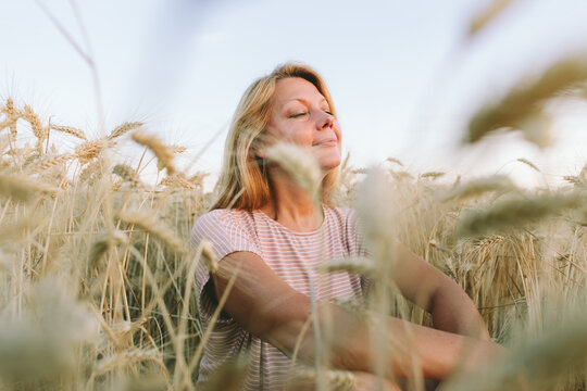 Woman relaxing in a wheat field enjoying nature and inner peace