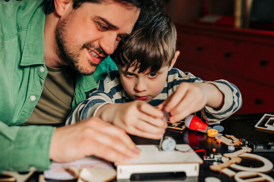 Father and son assemble an educational wooden toy kit at home
