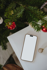 Top View Smartphone Mockup On White Table Near Decorated Christmas Tree © Floral Deco