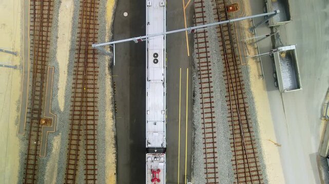 Top down view of a commuter train passing between parallel rail tracks in a maintenance depot yard