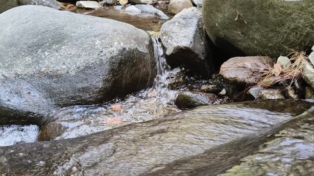 Small water stream flowing between large river rocks