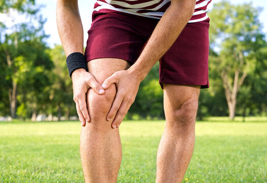 Person holding knee experiencing outdoor pain or discomfort