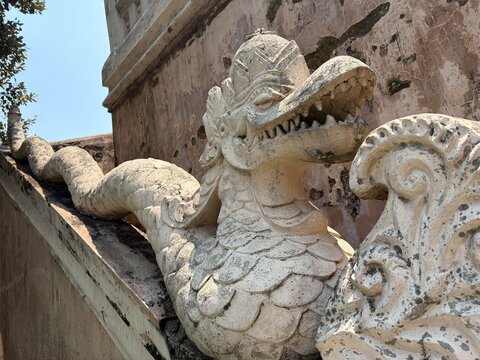 Mythological Javanese Naga serpent stone carving along a stairway balustrade at Tamansari Water Castle in Yogyakarta, Indonesia. Historic architectural landmark and cultural stone sculpture.