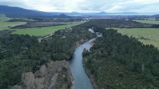 Winding river banks define the Tongariro River landscape in this aerial view of New Zealand surrounded by beautiful forests and peaceful natural scenery for tourism
