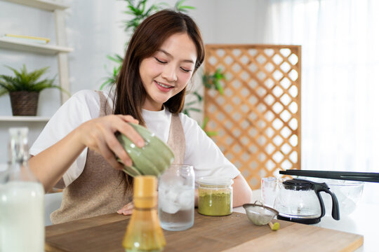 Asian young woman preparing matcha by stirring green tea powder in bowl. 