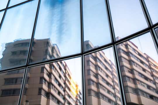 Reflection of modern buildings appears across glass windows in a geometric facade and turns the urban architecture into another view of the buildings through reflection