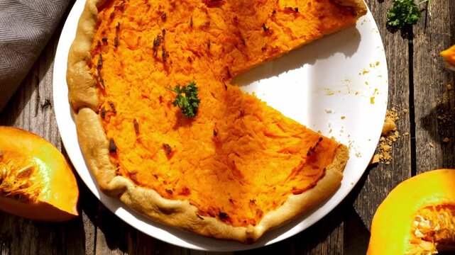 freshly baked homemade pumpkin pie with missing slice on wooden table