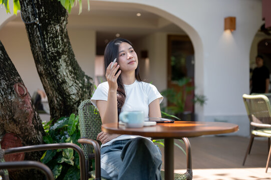 Asian Woman Freelancer Thinking with Stylus at Outdoor Cafe Table