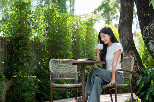 Asian Woman Drinking Coffee with Digital Tablet on Garden Patio