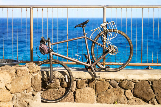 Bicycle resting against metal railing and stone wall along ocean