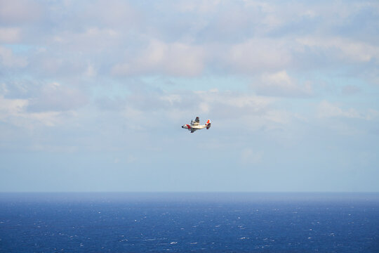 Airplane flying over ocean with distant horizon and clouds