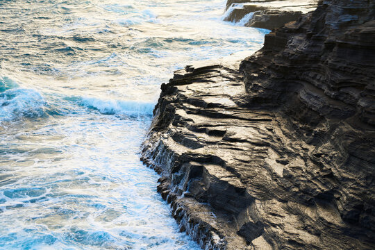 Ocean waves crashing on rocky cliff along Oahu coast