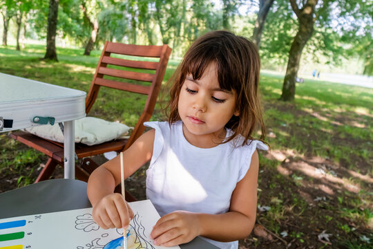 White child painting outdoors at a park table in a park