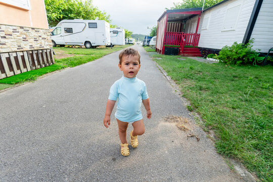 Toddler walking on path at campground with caravans