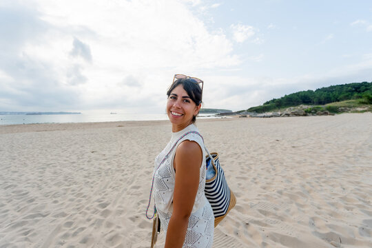 Smiling white woman enjoying time on sandy beach by the sea in a beach