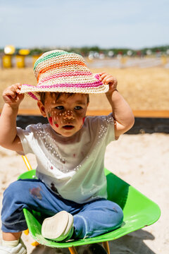 Toddler sitting with face paint in a wheelbarrow outdoors