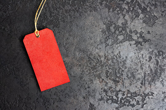 Blank red price tag with string on dark grunge background with copy space