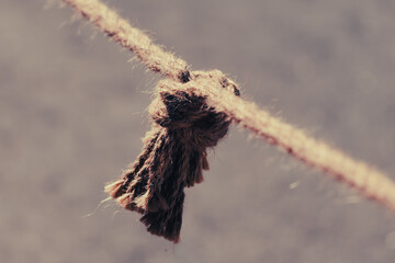 Worn rope knot hangs from taut line © schankz