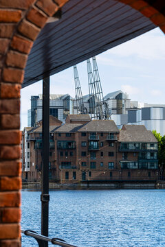Brick waterfront buildings in London create riverfront urban architecture where a layered skyline appears beyond the water and brick buildings