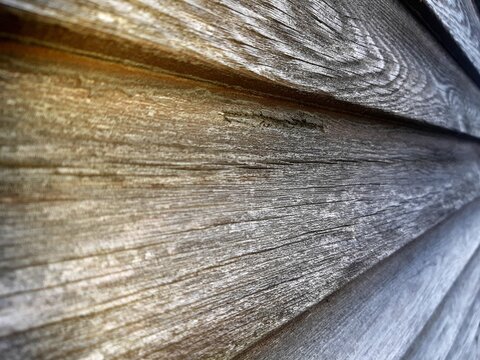 Close up of old weathered wooden planks wall texture with natural grain pattern, knots and vintage rustic surface. Horizontal timber paneling background for design and carpentry concept.