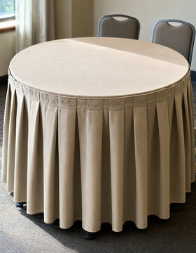 Round table with a pleated beige skirt and two chairs