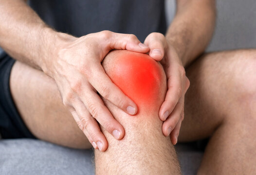Person Holding Painful Swollen Knee Joint Area With Hands