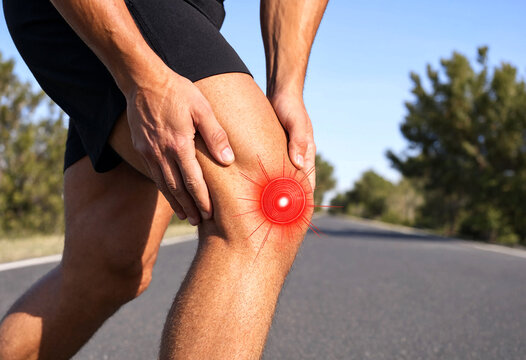 Person holding painful knee joint outdoors on roadway