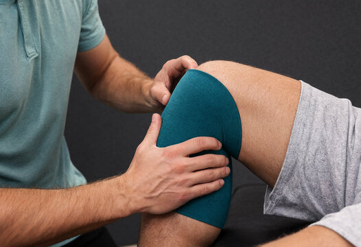 Person receiving knee compression therapy with blue wrap assistance