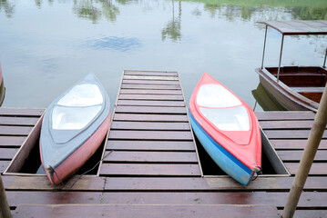 Colorful canoe boats on calm lake at mountain resort park Two colorful boats moored on wooden dock at peaceful lake surrounded by green hills and cloudy sky, ideal for travel leisure and recreation co © Ardy