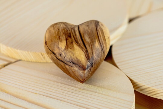Cuore di legno d'ulivo lavorato a mano su sfondo di legno di abete con venature	