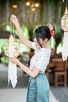 Beautiful Asian woman in traditional Thai dress holding paper lantern during Lanna Loy Krathong festival.