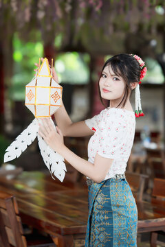Beautiful Asian woman in traditional Thai dress holding paper lantern during Lanna Loy Krathong festival.