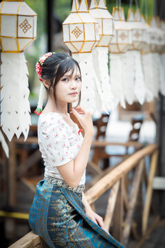 Beautiful Asian woman in traditional Thai dress holding paper lantern during Lanna Loy Krathong festival.