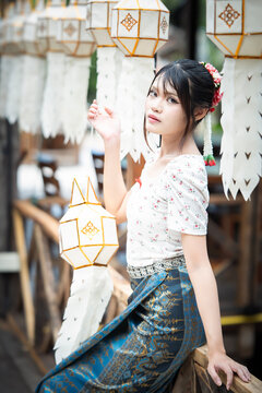 Beautiful Asian woman in traditional Thai dress holding paper lantern during Lanna Loy Krathong festival.