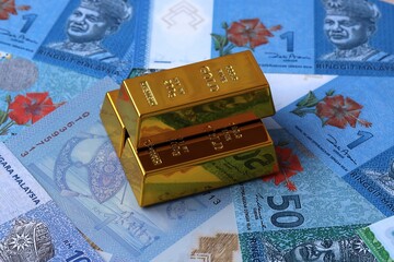 Malaysian ringgit money bills and gold bullion bars. Malaysia cash bills of MYR currency close up © Marharyta