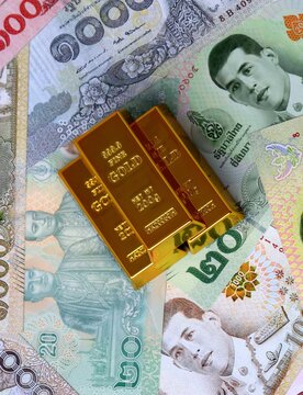Thai baht money bills and gold bullion bars. Thailand cash bills of THB currency close up