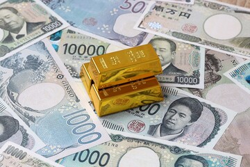 Japanese yen money bills and gold bullion bars. Japan cash bills of JPY currency close up © Marharyta