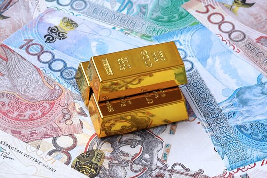 Kazakhstani tenge money bills and gold bullion bars. Kazakhstan cash bills of KZT currency close up