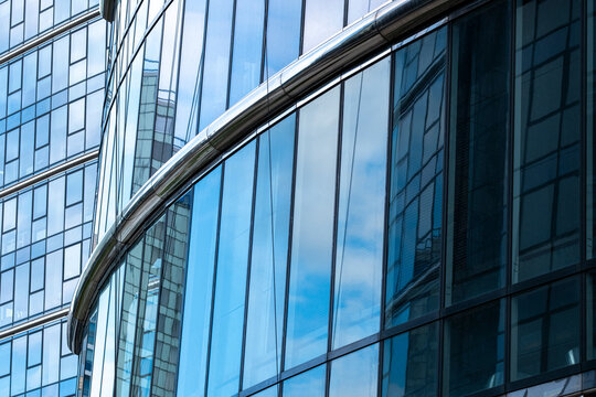 Blue reflective glass facade with a curved edge creates abstract architecture where transparency and lines follow the curved edge across the blue glass facade