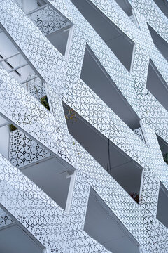 White perforated facade with balconies creates abstract architecture where geometry and pattern shape the modern structure across the white facade and balconies