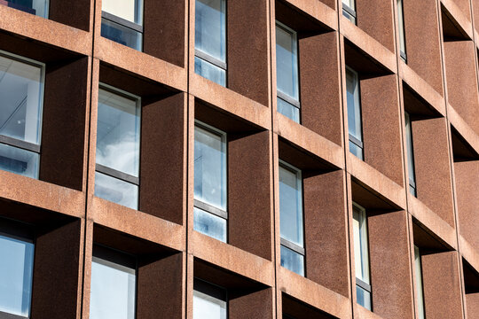 Brown facade with windows creates abstract architecture where repetition geometry and warm tones shape the brown surface across the facade and windows